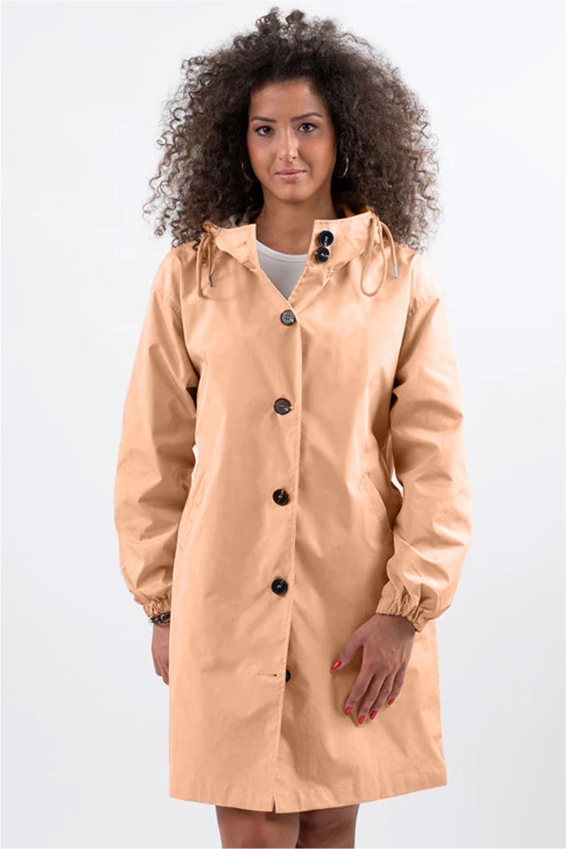 Woman wearing beige oversized Rain Couture Windbreaker water-resistant jacket with hood and button closure
