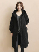 Woman wearing black oversized Rain Couture Windbreaker water-resistant jacket with hood and button closure
