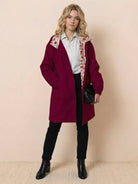 Woman wearing burgundy oversized Rain Couture Windbreaker with floral hood lining and black pants