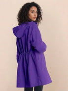 Woman wearing oversized purple Rain Couture Windbreaker jacket with hood, back view