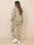 Woman wearing ultra-soft and comfy co-ord tracksuit set in khaki color, standing against beige background