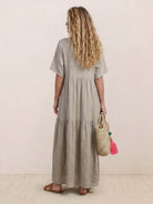 Women wearing V-neck two-tiered maxi swing dress in flowing cotton fabric with irregular hem and draped sleeves.