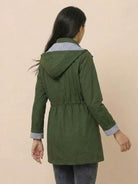 Back view of a woman wearing a green water resistant windbreaker with hood and striped inner lining